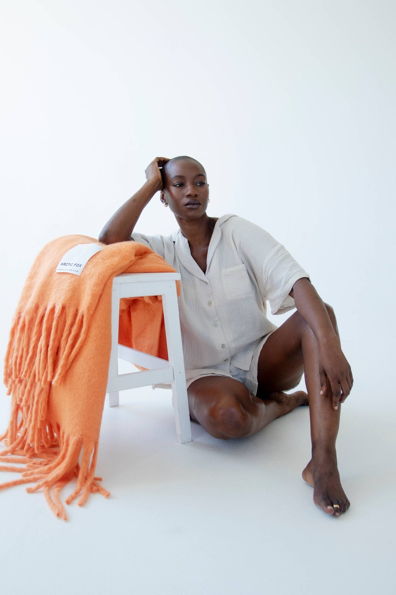 lady leaning on a stool with an orange blanket thrown over it