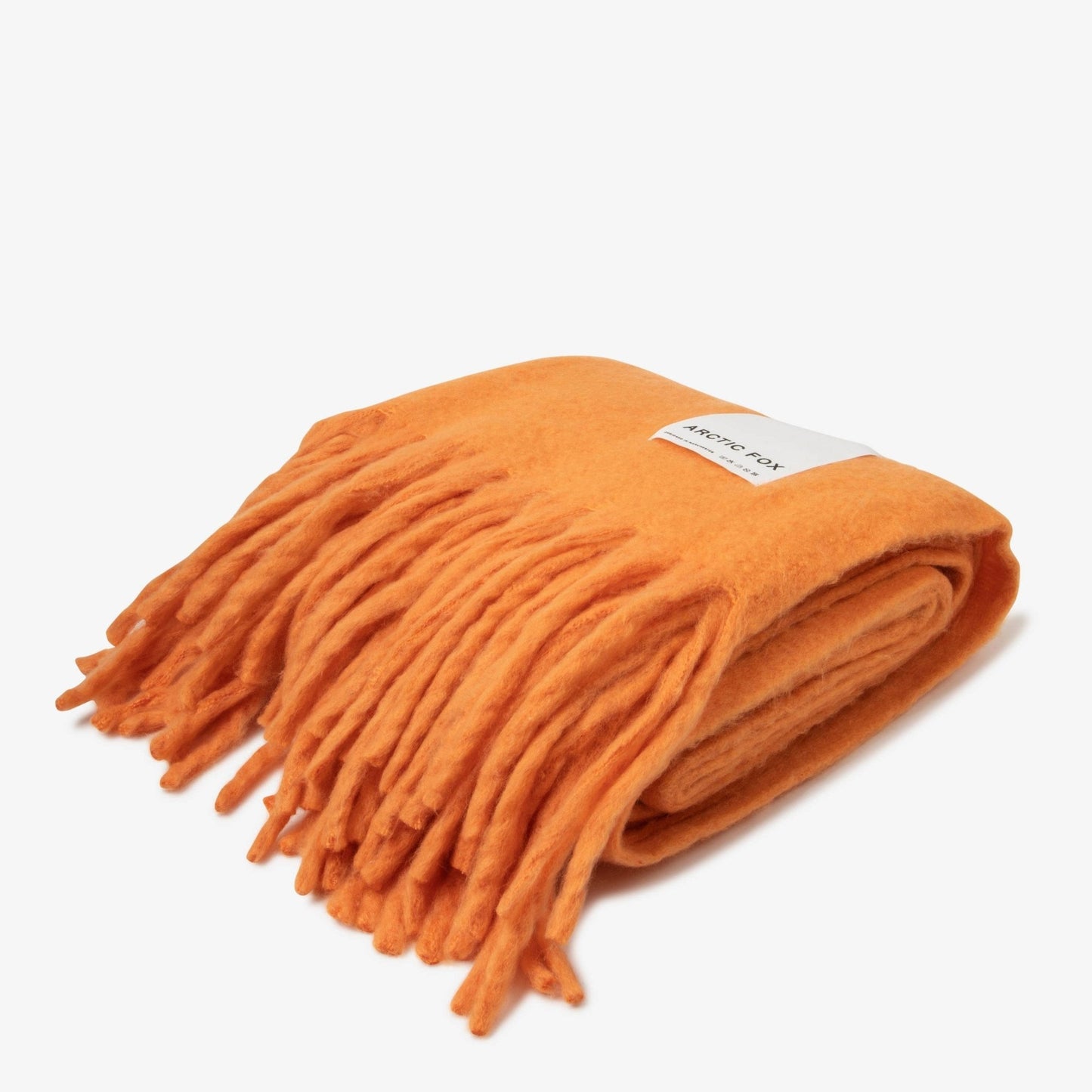 folded orange blanket with tassels