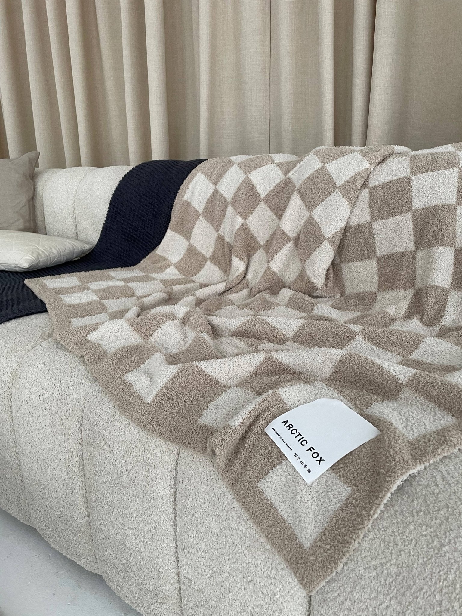 cheque beige blanket thrown over a cream sofa