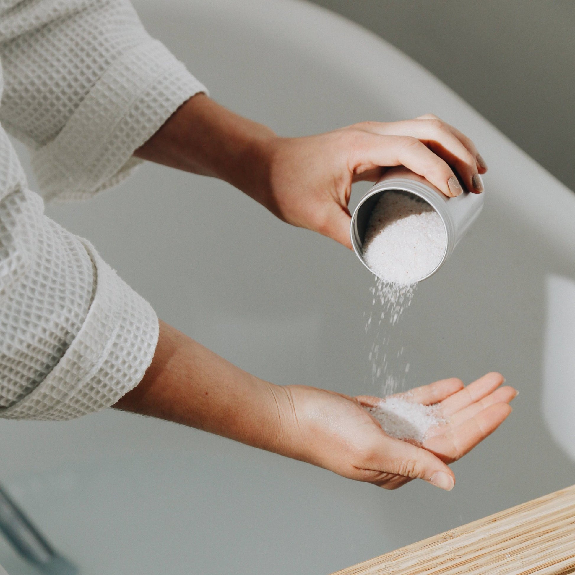 hand pouring bergamot bath salts into another hand