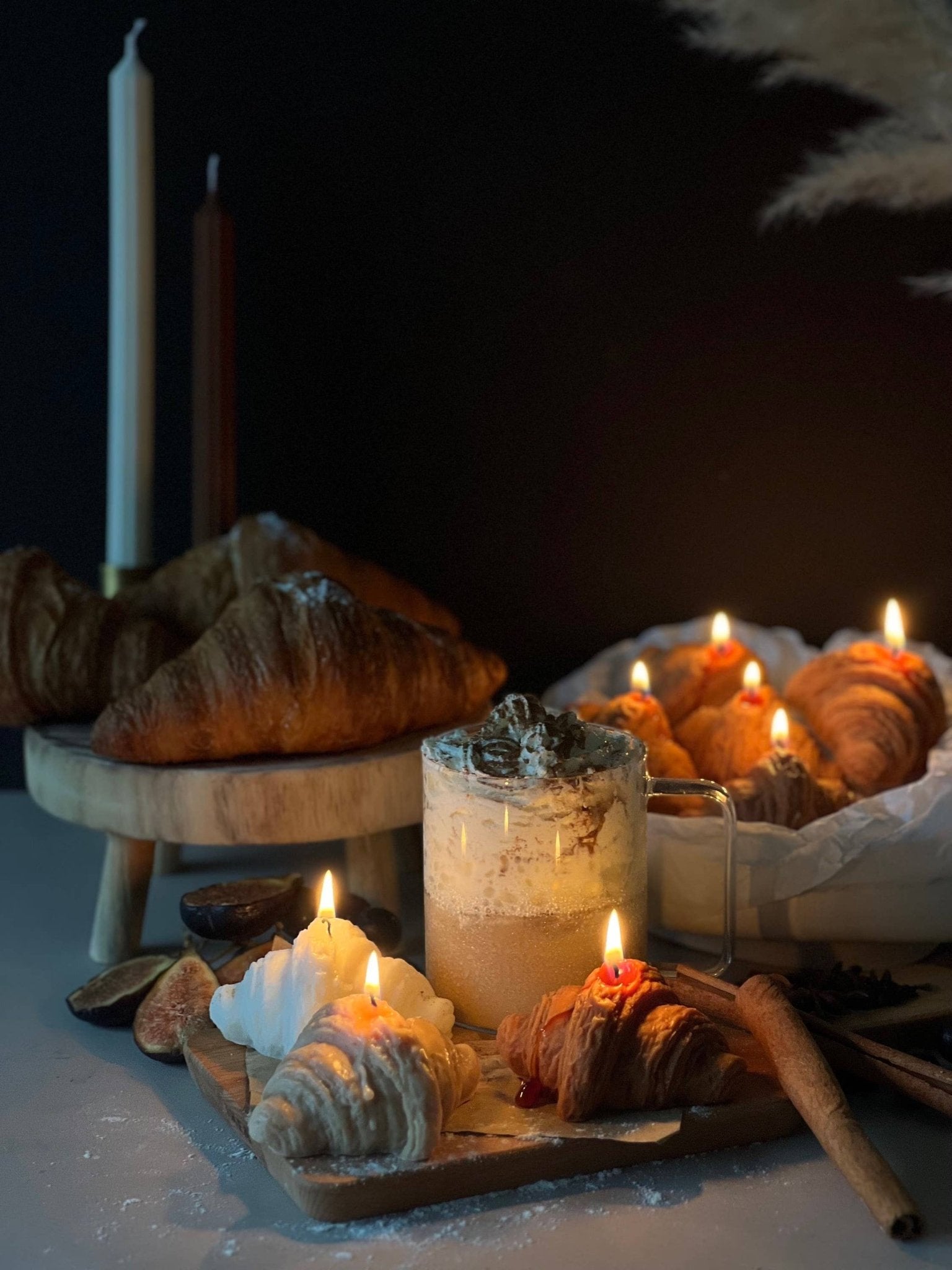 croissant shaped candles lit beside a hot chocolate