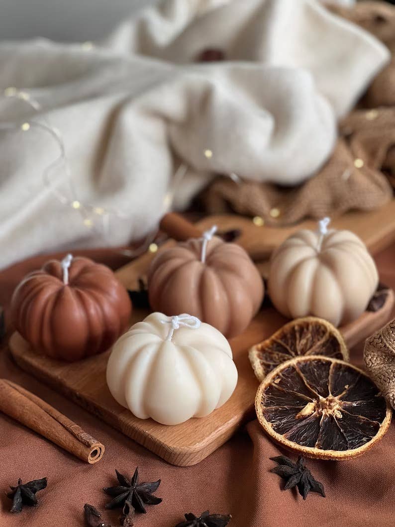 neutral pumpkin shaped candles on a wooden board