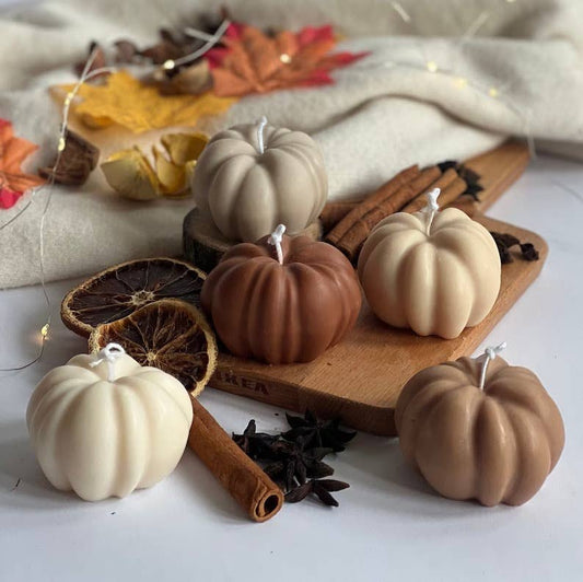 selection of neutral pumpkin shaped candles on a wooden board